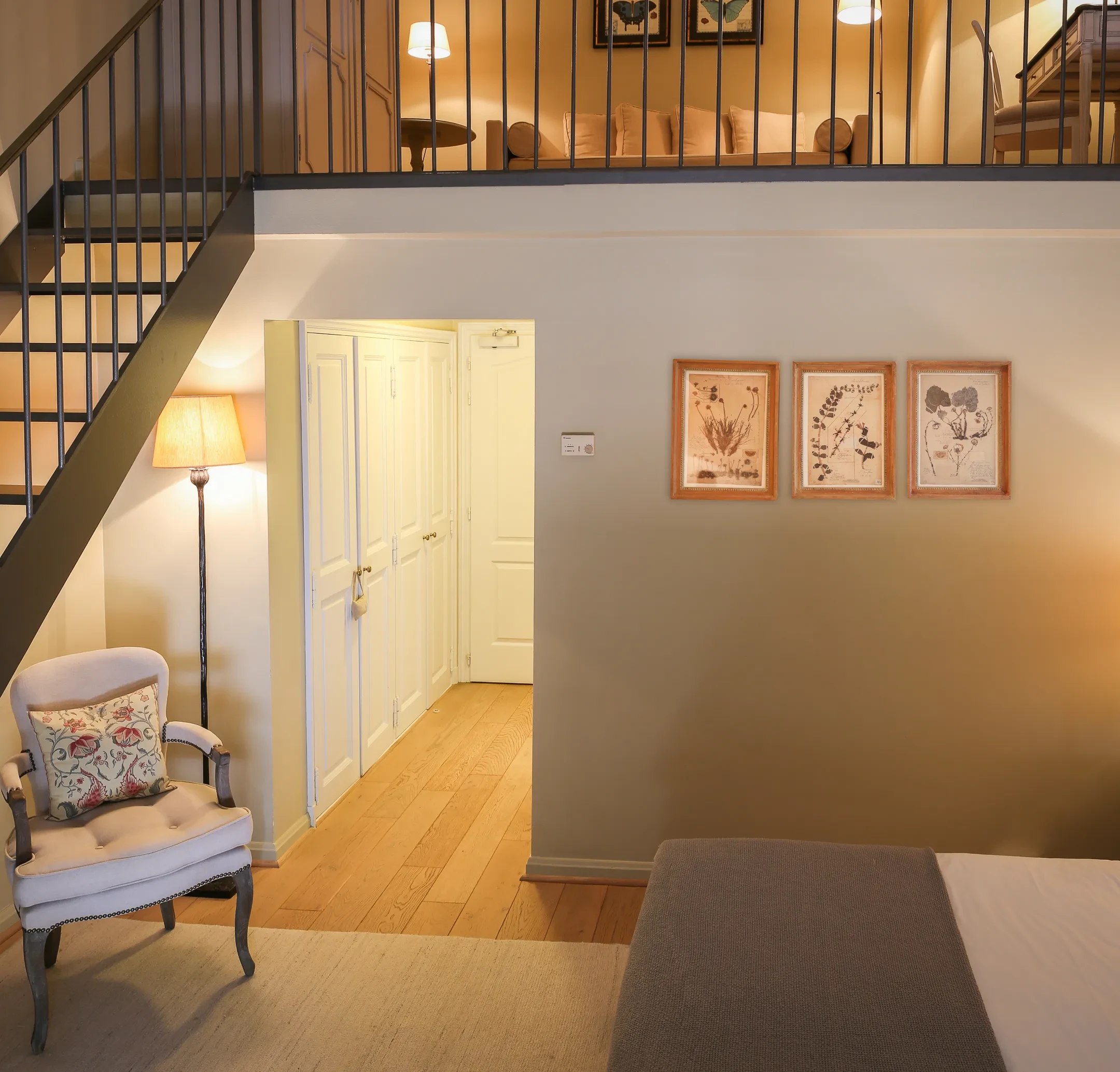 Intérieur d'une chambre avec mezzanine, fauteuil, et lampadaire.